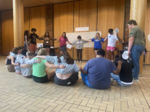 Students sitting and standing in a circle in the chapel holding hands. 